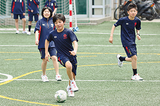 校庭でサッカーをする生徒