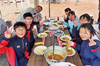 キャンプでカレーを食べる生徒たち